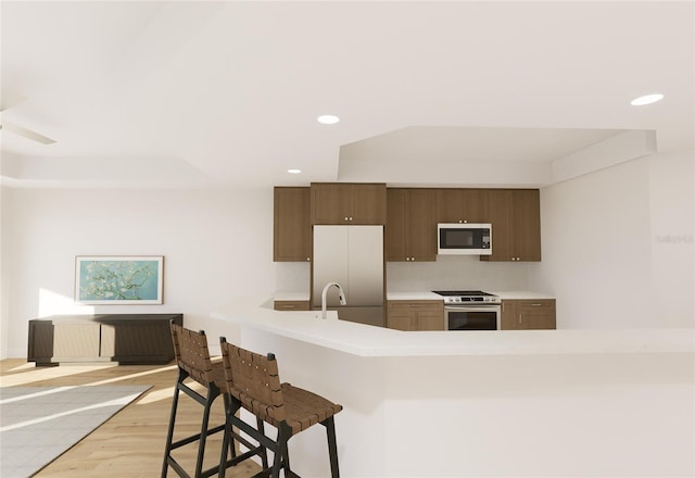 kitchen featuring white microwave, a breakfast bar area, stainless steel stove, light countertops, and fridge