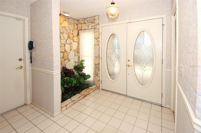 entrance foyer featuring light tile patterned floors, a textured ceiling, and french doors