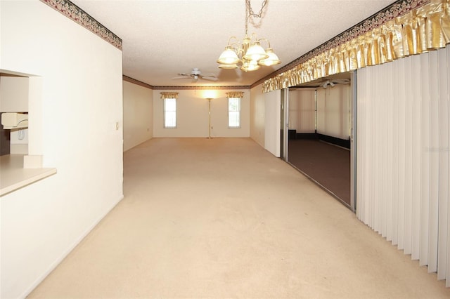 interior space with ornamental molding, a textured ceiling, and ceiling fan with notable chandelier