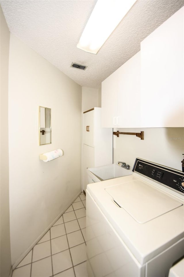 clothes washing area featuring washer / dryer, light tile patterned floors, laundry area, visible vents, and a textured ceiling