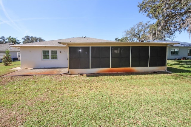 rear view of property with a patio, a yard, a sunroom, and stucco siding