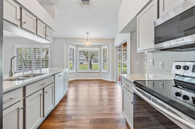 kitchen with light countertops, appliances with stainless steel finishes, a sink, and visible vents