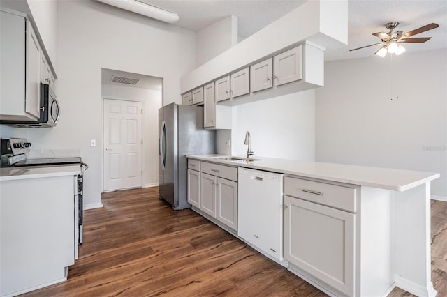 kitchen featuring stainless steel appliances, dark wood-type flooring, a sink, visible vents, and light countertops