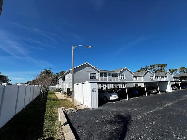 view of side of property featuring covered parking, a residential view, and fence