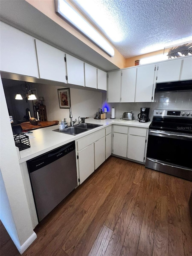 kitchen with light countertops, appliances with stainless steel finishes, white cabinetry, a sink, and under cabinet range hood