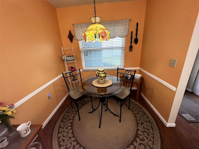 dining space with baseboards and wood finished floors