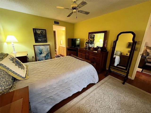 bedroom with a textured ceiling, wood finished floors, a ceiling fan, visible vents, and baseboards