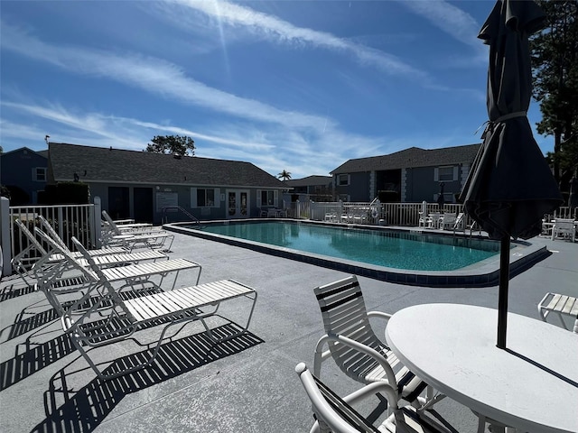 community pool featuring a residential view, a patio area, and fence