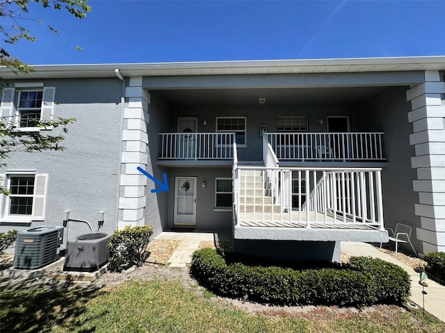 12027 Hoosier Ct Unit 104, Hudson, FL 34667 - rear view of property with cooling unit, stucco siding, stairs, and covered porch