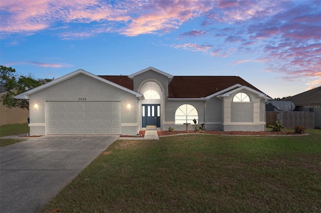 single story home featuring a garage, a yard, concrete driveway, and stucco siding