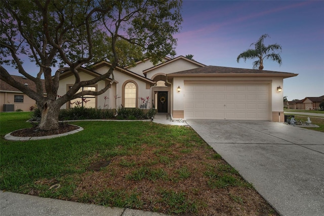 ranch-style house featuring a yard, stucco siding, an attached garage, central AC unit, and driveway