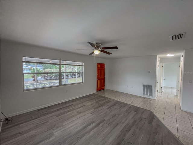 unfurnished room with a ceiling fan, light wood-style flooring, visible vents, and baseboards