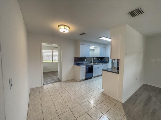 kitchen with black dishwasher, visible vents, white cabinets, dark countertops, and a sink