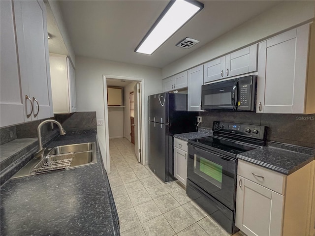 kitchen featuring dark countertops, visible vents, white cabinets, a sink, and black appliances