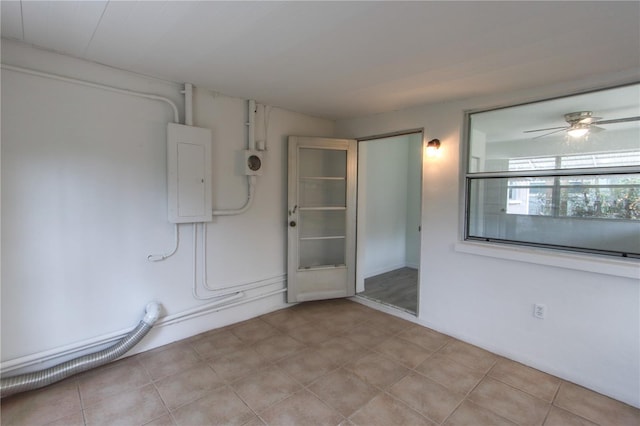 empty room with light tile patterned floors, electric panel, and a ceiling fan