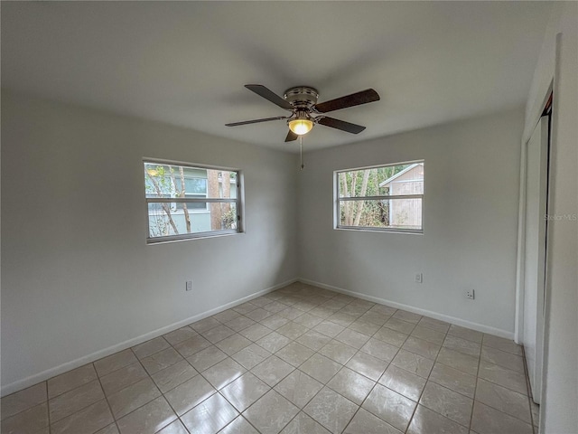 unfurnished room with a ceiling fan, light tile patterned flooring, and baseboards