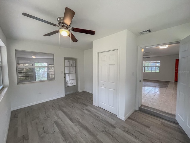 empty room with a ceiling fan, baseboards, visible vents, and wood finished floors