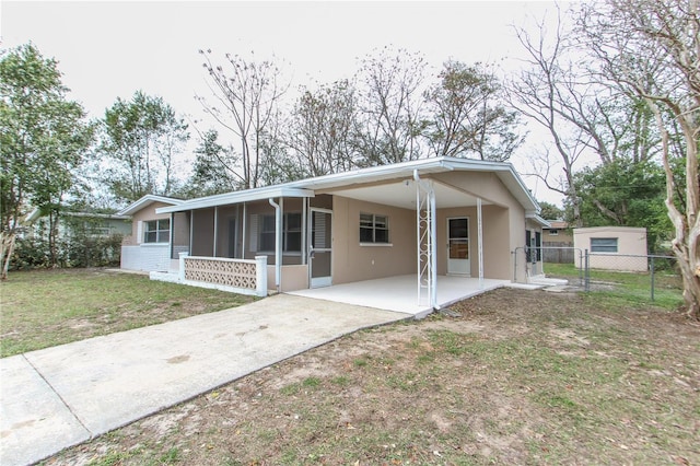 single story home featuring driveway, a carport, a front yard, and a sunroom