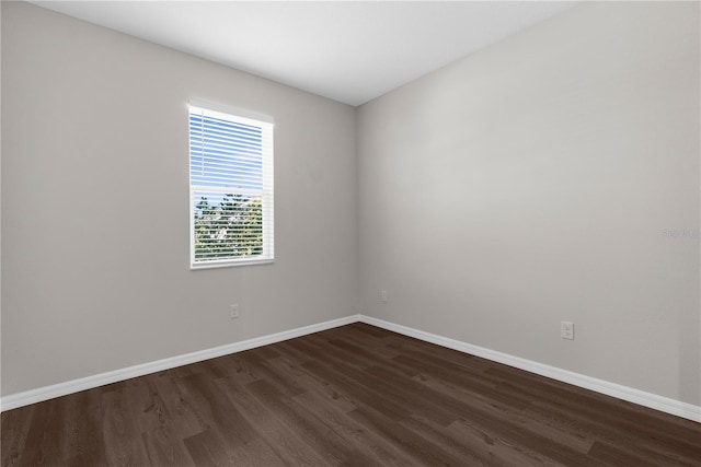 spare room featuring dark wood-style flooring and baseboards