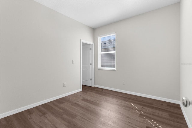 empty room featuring dark wood finished floors and baseboards