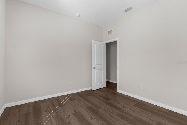 empty room featuring baseboards, visible vents, and dark wood finished floors