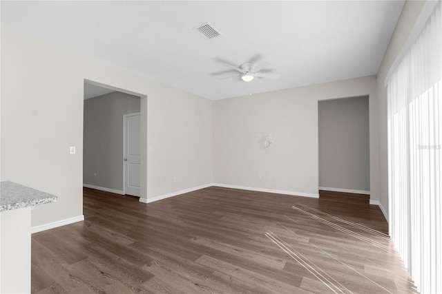 unfurnished room with ceiling fan, dark wood finished floors, visible vents, and baseboards