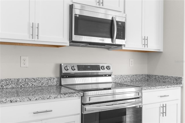 kitchen featuring stainless steel appliances, white cabinets, and light stone countertops