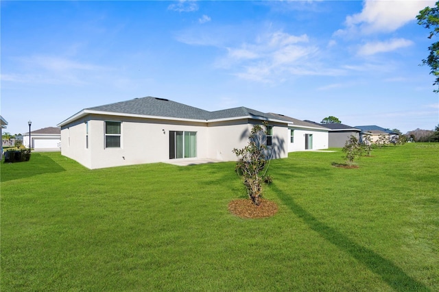 back of property featuring roof with shingles, a lawn, and stucco siding