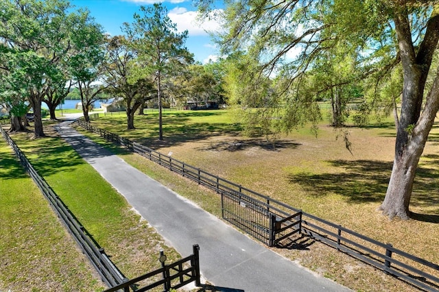 surrounding community with fence, a lawn, and a water view