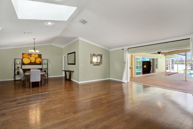 unfurnished living room featuring visible vents, lofted ceiling with skylight, a chandelier, ornamental molding, and wood finished floors