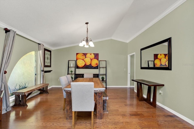 dining area featuring a notable chandelier, wood finished floors, crown molding, baseboards, and vaulted ceiling