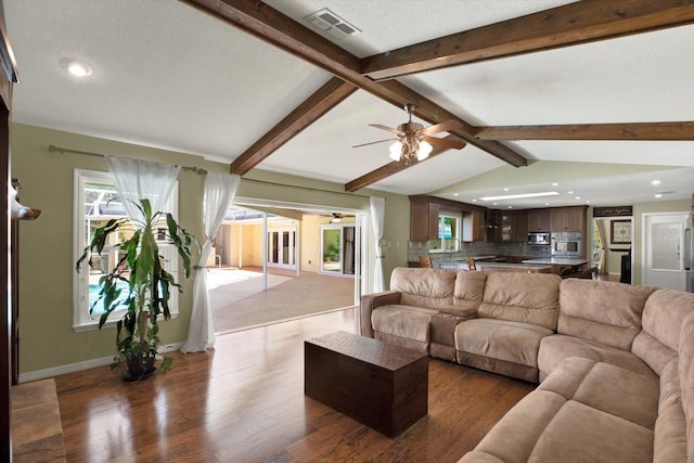 living room featuring visible vents, baseboards, lofted ceiling with beams, wood finished floors, and a textured ceiling