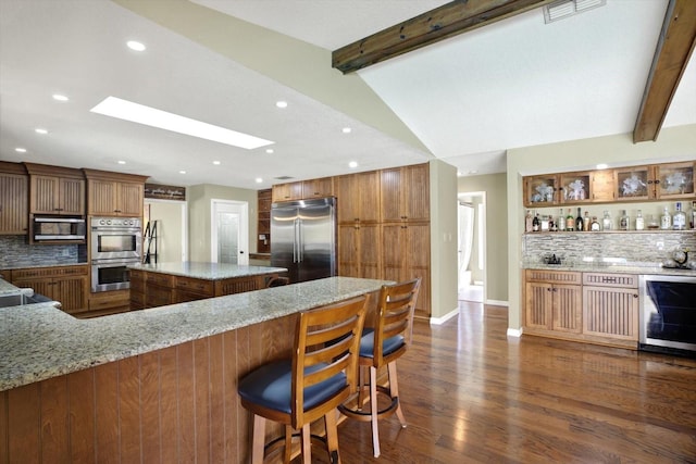 kitchen featuring brown cabinetry, stainless steel appliances, visible vents, and decorative backsplash