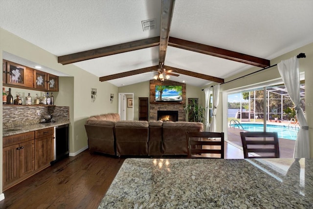 living area featuring a dry bar, vaulted ceiling with beams, dark wood-style flooring, and a textured ceiling