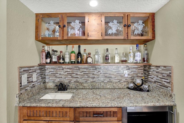 bar featuring a sink, indoor wet bar, beverage cooler, and decorative backsplash