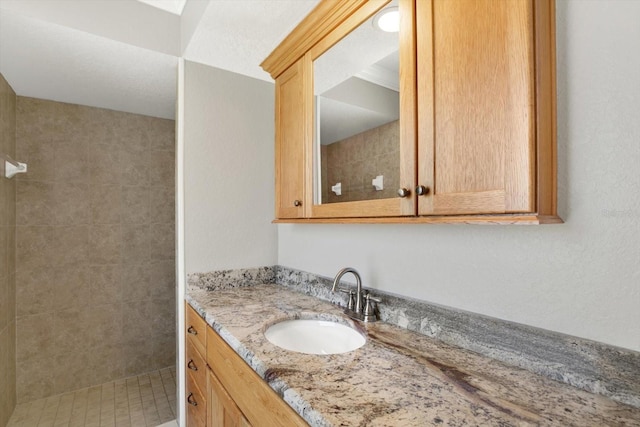 bathroom featuring a tile shower and vanity