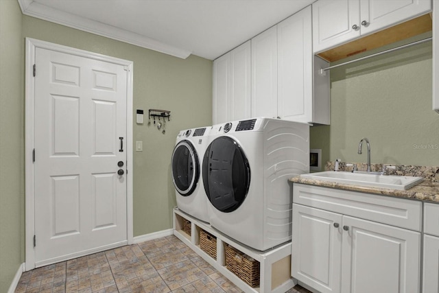 clothes washing area featuring a sink, crown molding, baseboards, cabinet space, and separate washer and dryer