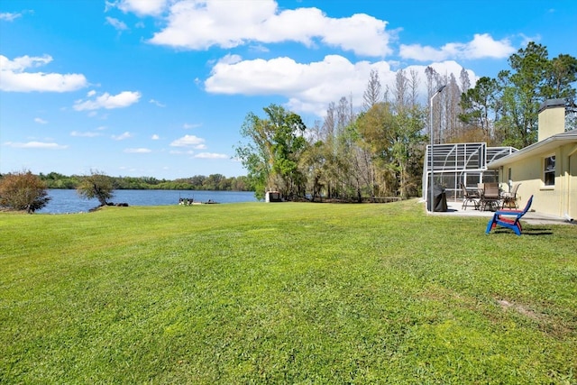 view of yard featuring glass enclosure, a patio, and a water view