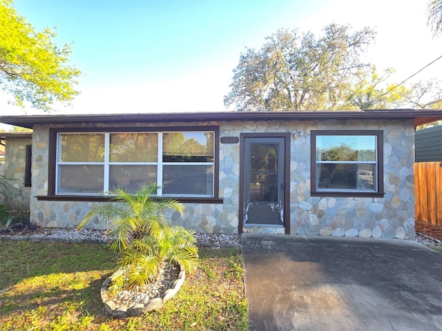 view of front of home with stone siding and fence