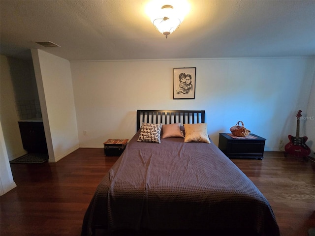 bedroom featuring visible vents, baseboards, and wood finished floors