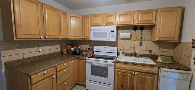 kitchen featuring white appliances, light tile patterned floors, a sink, dark countertops, and tasteful backsplash