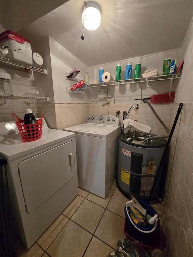 laundry room featuring water heater, laundry area, light tile patterned floors, tile walls, and separate washer and dryer