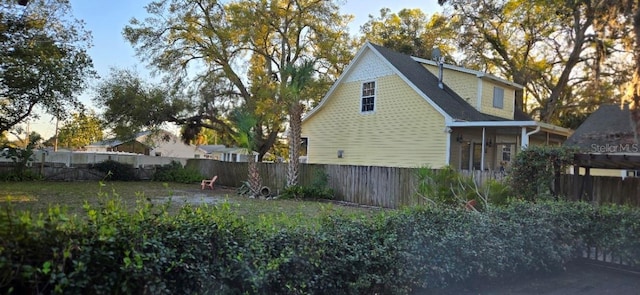 view of home's exterior with a fenced backyard and a sunroom