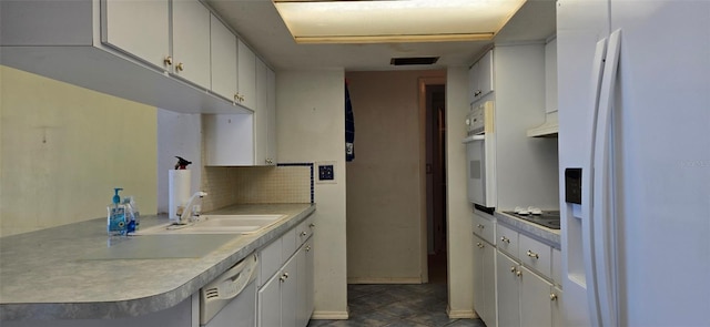 kitchen featuring a sink, white appliances, backsplash, and light countertops