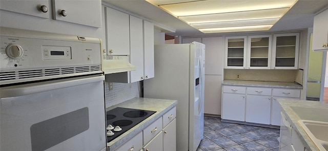 kitchen featuring tasteful backsplash, white cabinetry, white appliances, exhaust hood, and light countertops