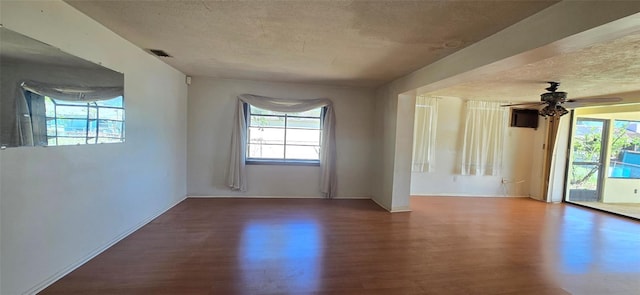 empty room featuring ceiling fan, visible vents, a textured ceiling, and wood finished floors