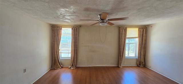 spare room with ceiling fan, plenty of natural light, and wood finished floors