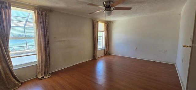 unfurnished room with plenty of natural light, a textured ceiling, ceiling fan, and wood finished floors