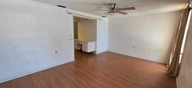 unfurnished room with visible vents, a textured ceiling, ceiling fan, and wood finished floors