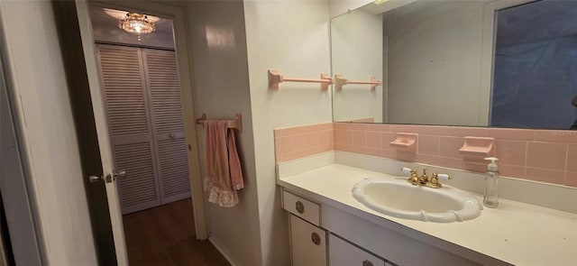 bathroom featuring vanity, wood finished floors, tasteful backsplash, and baseboards